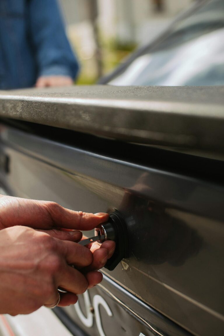 Close-up of hands unlocking a car trunk with a key, focusing on detail.